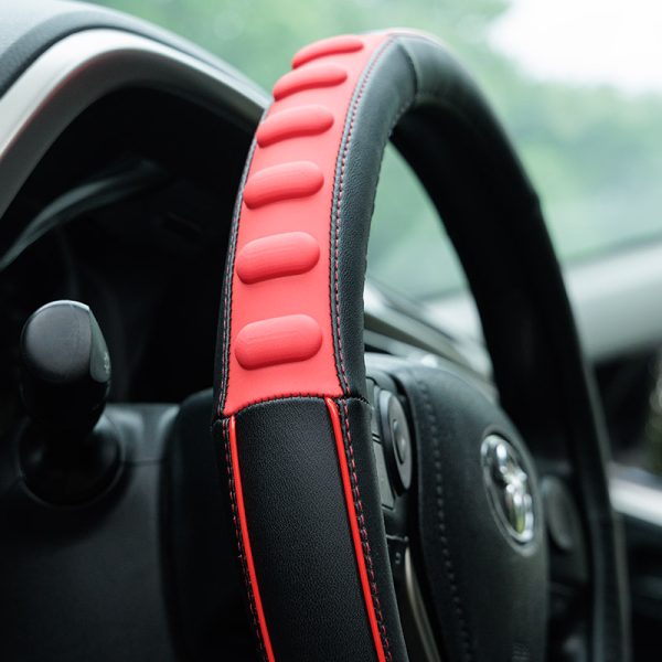 Close-up of red raised pads on 3D massage steering wheel cover 80627 installed in a car
